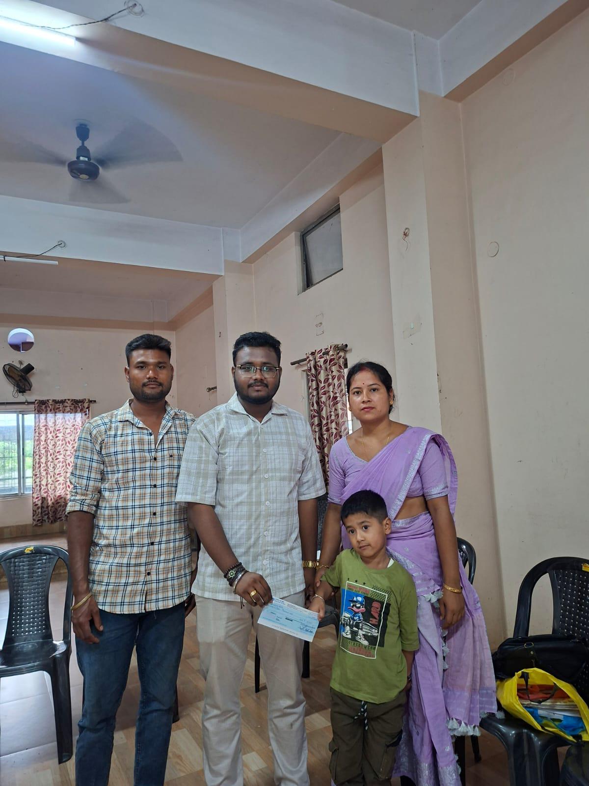 Trust volunteer handing over a financial assistance cheque to a beneficiary family under Kalyan Kiran